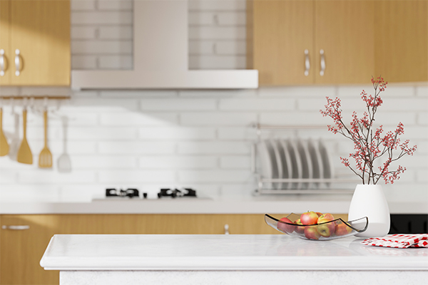 Close-up Marble kitchen counter island with apples in a modern bowl, napkin and decor over blurred white and wooden kitchen room. 3d rendering, 3d illustration